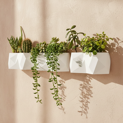 White wall-mounted planter with green plants in a bright room.
