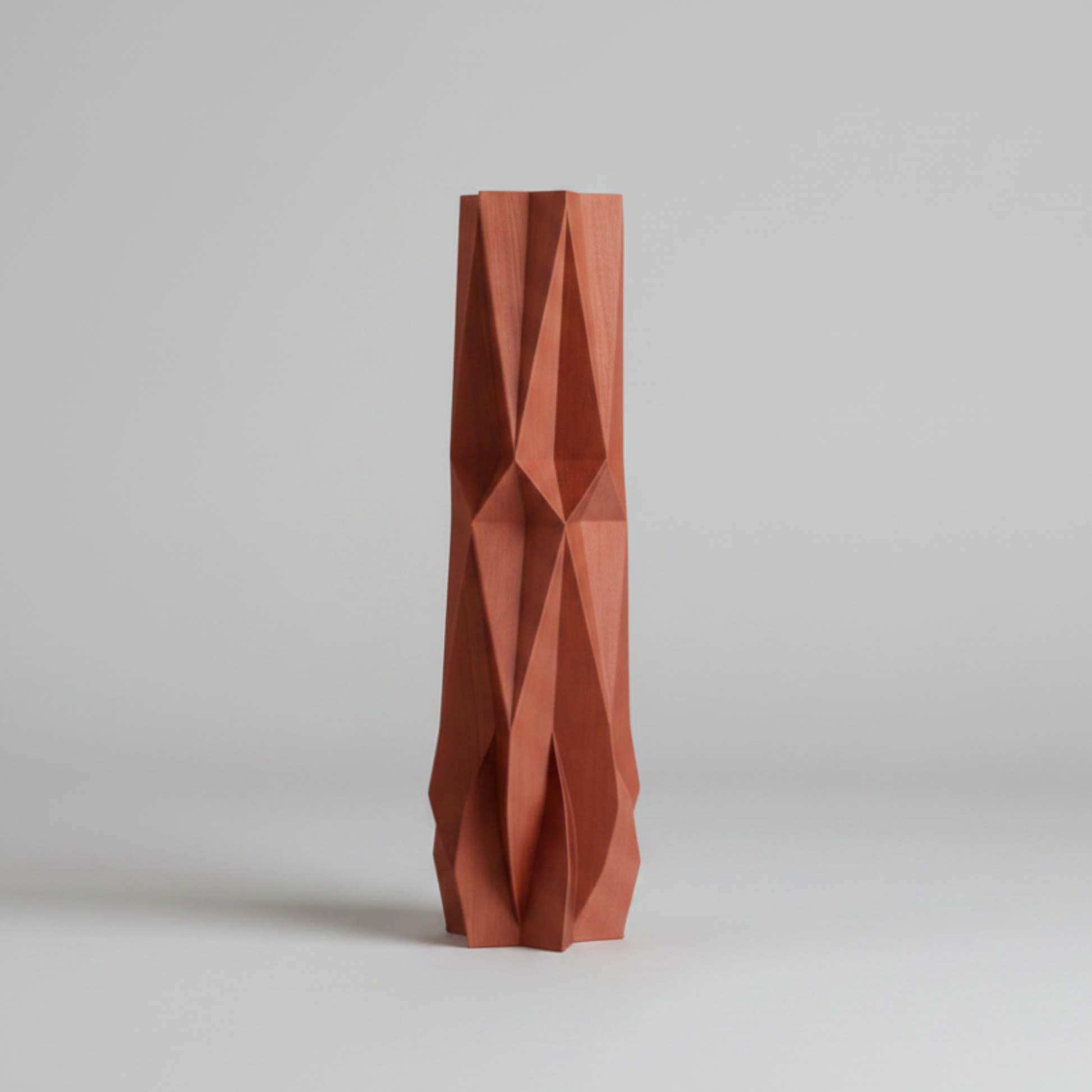 An abstract geometric vase, standing upright on a neutral light gray background.