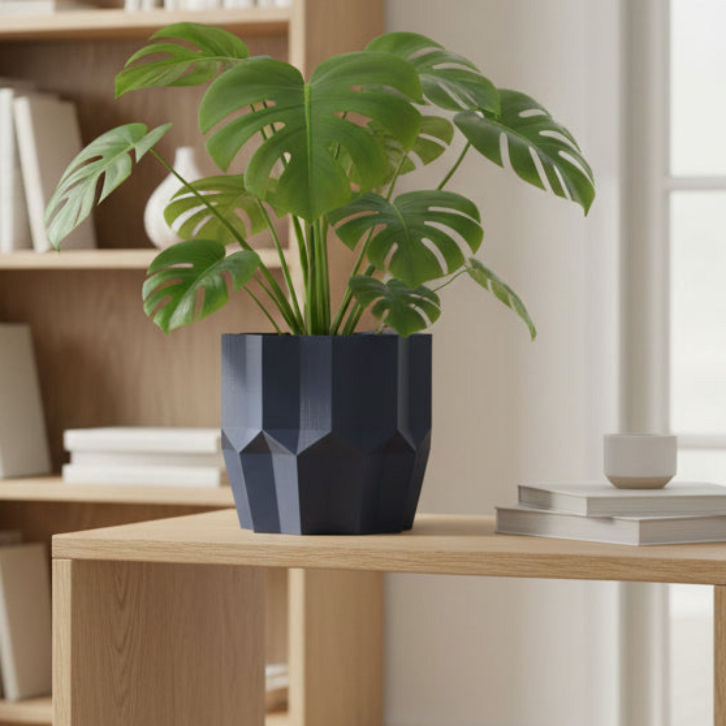 Potted plant in a geometric blue pot on a wooden table with a bookshelf in the background.