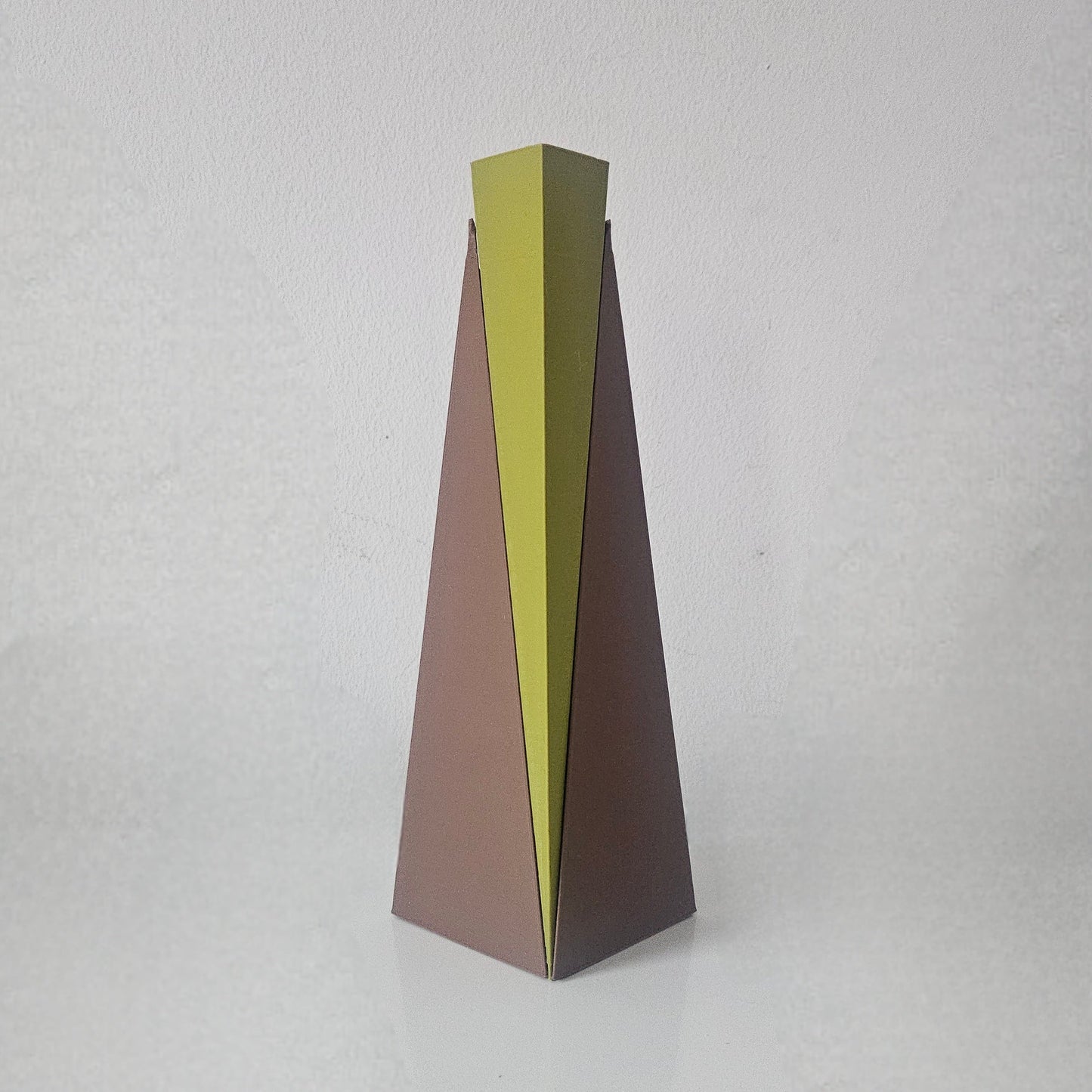Tall, thin vase with a gradient color from green to brown on a light gray background